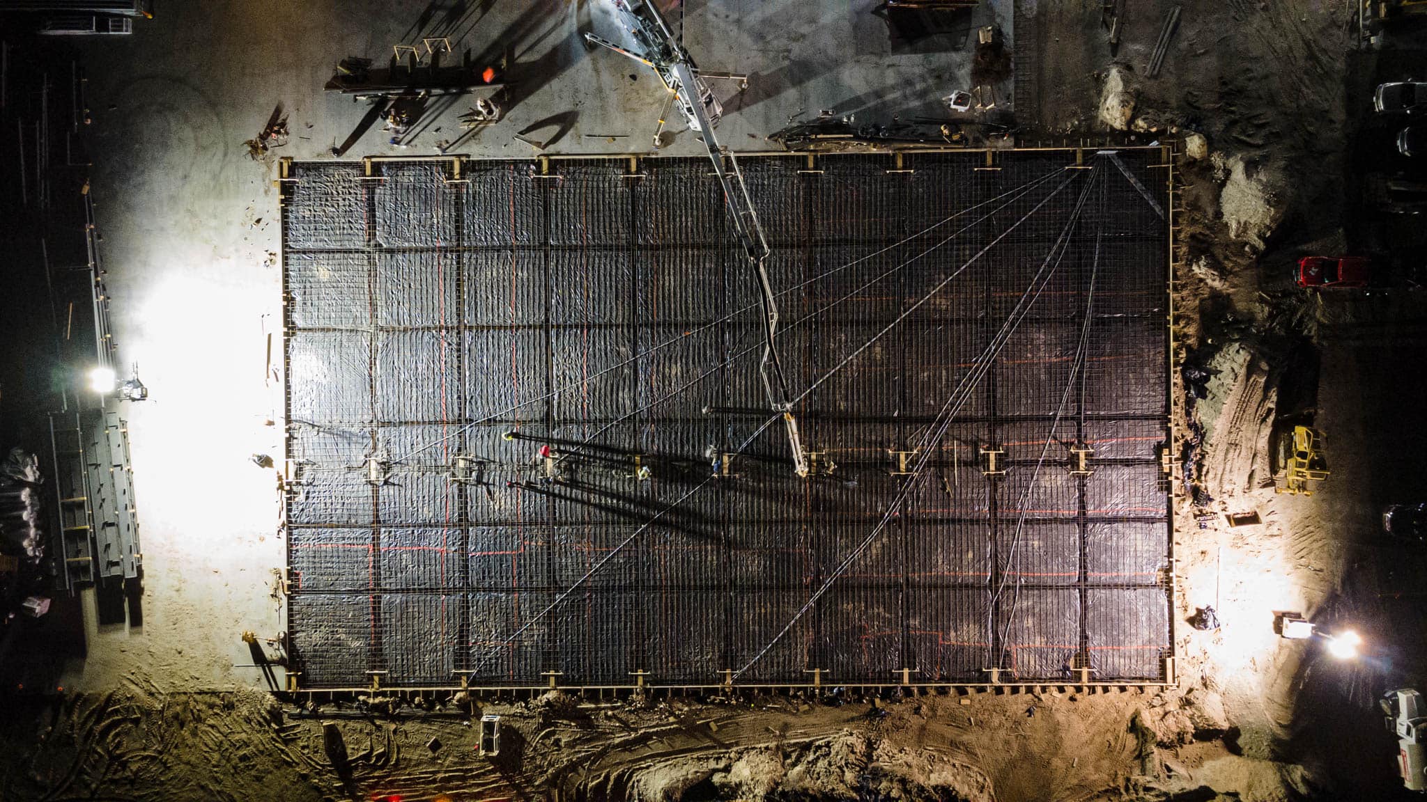 Aerial close-up at night of a rebar foundation grid ready for a concrete pour
