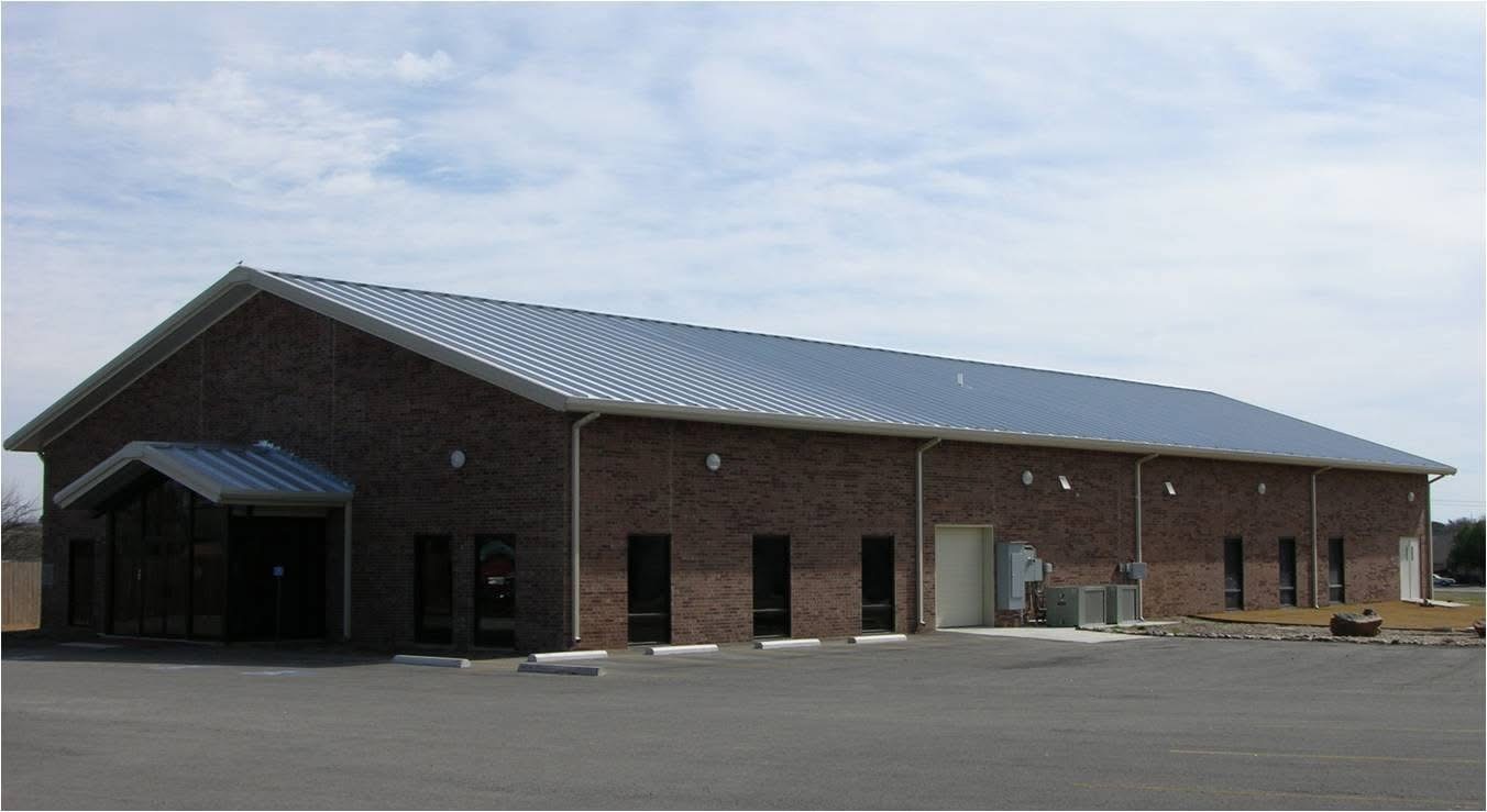Large brick commercial metal building with gable roof and multiple entry doors