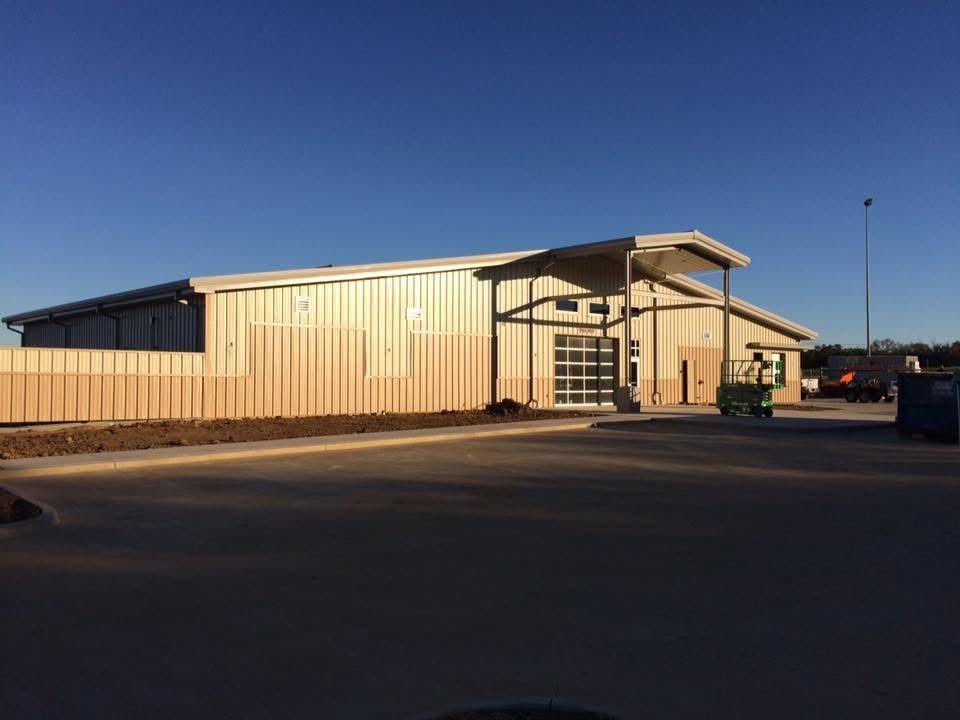 Tan steel commercial building with covered entry canopy lit by evening sun