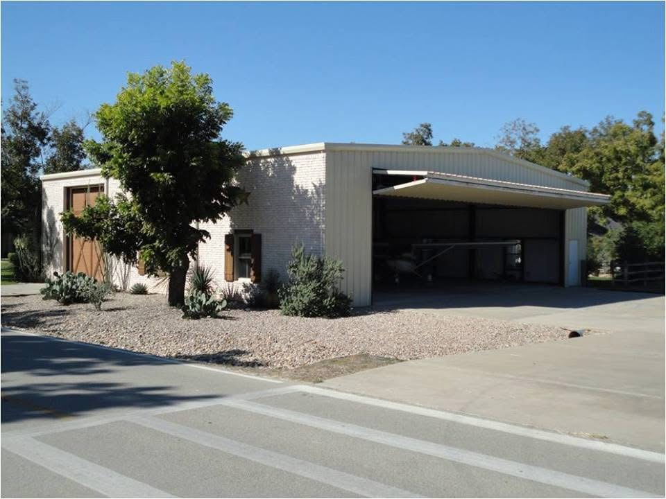 Beige brick and steel airport hangar with landscaped entrance and open bay door