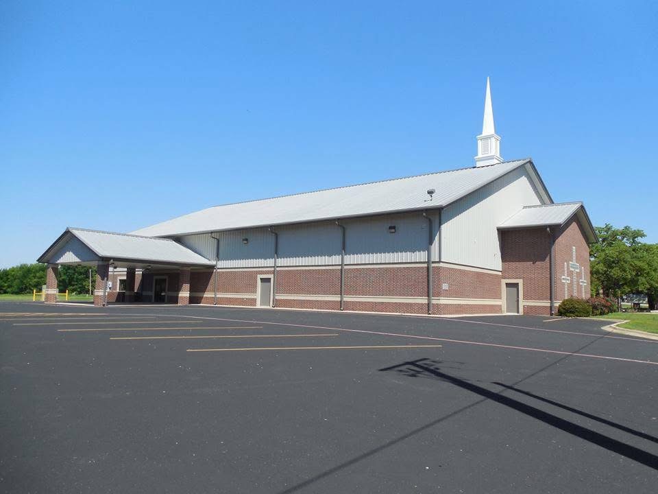 Brick and steel church building with white steeple and covered drop-off canopy